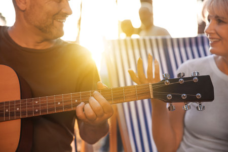 Mature man playing guitar at barbecue party outdoors, closeup