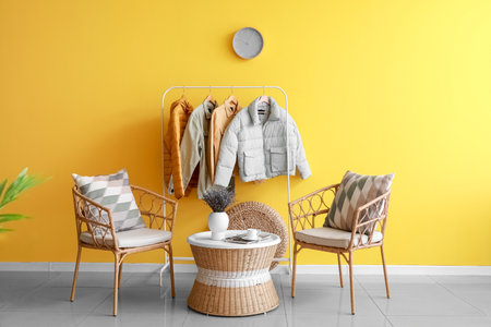 Interior of room with comfortable chairs and hanger with jackets near color wallの写真素材
