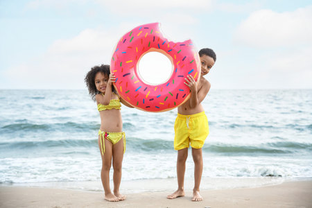 African-American children with inflatable ring on sea beach