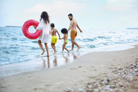 Happy family with inflatable ring on sea beachの写真素材