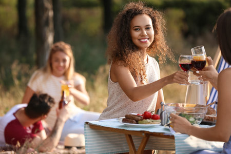Young woman drinking wine with friends at barbecue party on summer dayの写真素材