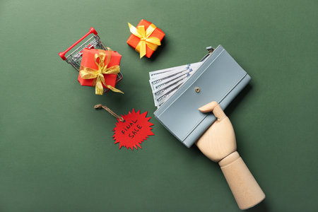 Wooden hand with wallet, money, shopping cart, gift boxes and tag with text FINAL SALE on color backgroundの写真素材