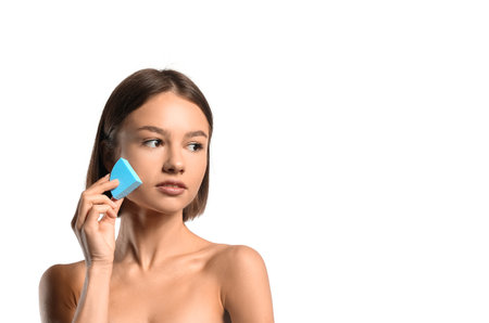 Pretty young woman with blue makeup sponge on white backgroundの写真素材