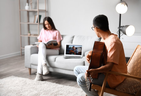 Young man having online guitar lesson at homeの写真素材