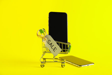 Shopping cart, mobile phones and tag with text SALE on color backgroundの写真素材