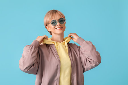 Beautiful young woman in stylish hoodie on color backgroundの写真素材