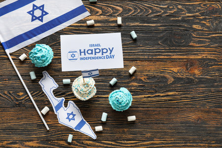 Delicious cupcakes, flag of Israel and card with text HAPPY INDEPENDENCE DAY on wooden backgroundの写真素材