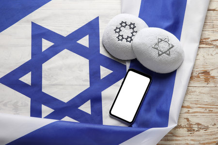 Flag of Israel, kippahs and mobile phone on light wooden backgroundの写真素材