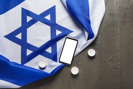 Flag of Israel, burning candles and mobile phone on dark wooden backgroundの写真素材