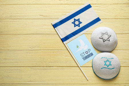 Kippahs, flag of Israel and card with text STOP TERRORISM on color wooden backgroundの写真素材