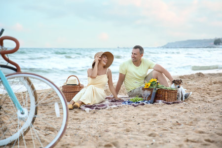 Mature couple having picnic near sea on summer dayの写真素材