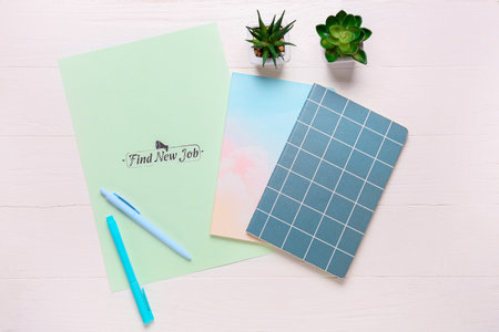 Paper sheet with text FIND NEW JOB and stationery on white wooden background. new year goals