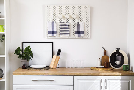 Stylish counter and pegboard on white wall in modern kitchen