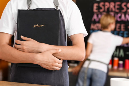 Young male barista with menu in cafe, closeupの写真素材