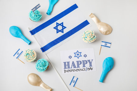 Flag of Israel, cupcakes and card with text HAPPY INDEPENDENCE DAY on light backgroundの写真素材