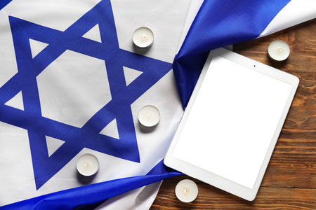 Modern tablet computer, candles and flag of Israel on wooden backgroundの写真素材