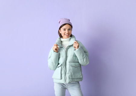 Pretty young woman in stylish warm clothes on color backgroundの写真素材