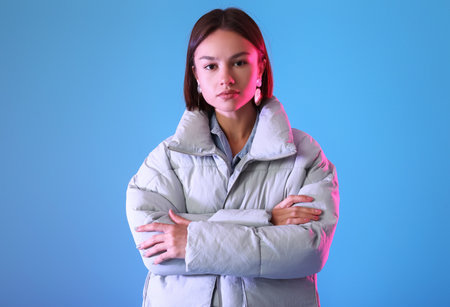 Pretty young woman in stylish warm clothes on color backgroundの写真素材