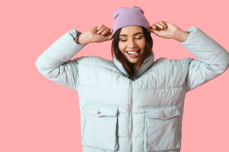Cute young woman in stylish warm clothes on color backgroundの写真素材