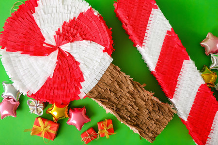 Mexican pinatas with balloons and gifts on green background