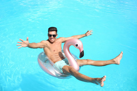 Young man with inflatable ring in swimming poolの写真素材
