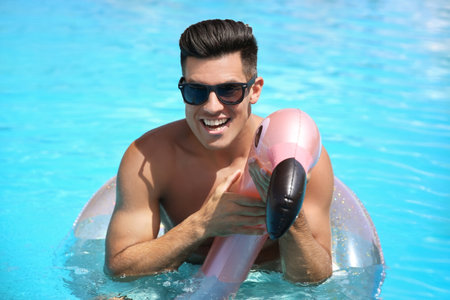 Young man with inflatable ring in swimming poolの写真素材