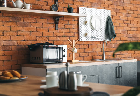 Interior of modern kitchen with counters and hanging pegboard on brick wallの写真素材