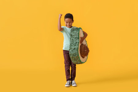 Little boy with Mexican pinata on color background