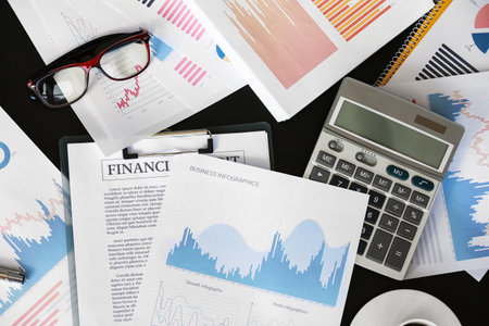 Business documents, calculator and eyeglasses on desk in office