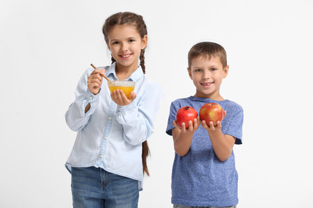 Little children with fruits and honey on white background. Rosh Hashanah (Jewish New Year) celebrationの写真素材