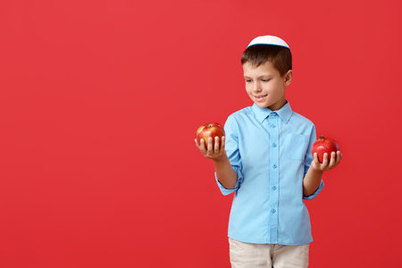 Little boy with apple and pomegranate on color background. Rosh Hashanah (Jewish New Year) celebrationの写真素材