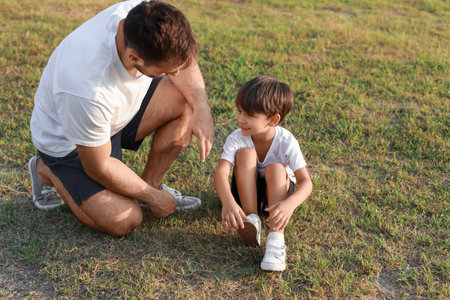 Father and his little son with bruised knee after playing soccer on fieldの写真素材