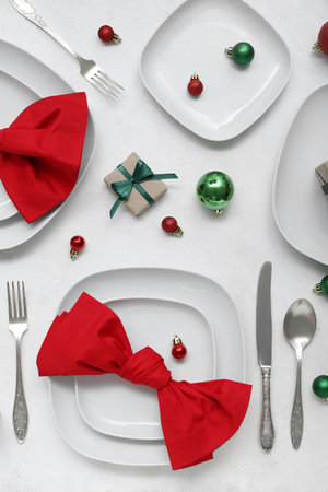 Beautiful table setting with Christmas balls and gift on white backgroundの写真素材