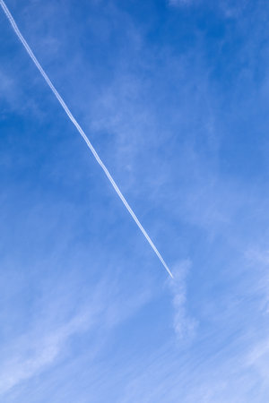 White contrails of plane in blue skyの写真素材