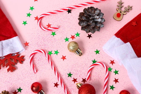 Composition with Christmas decorations, candy canes and confetti on pink background, closeup
