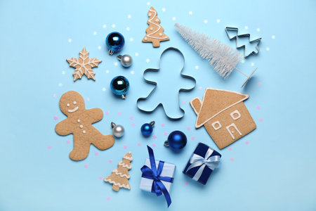 Composition with tasty Christmas cookies, cutters, gifts and decorations on color background