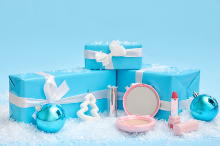 Makeup products with presents, Christmas decor and snow on blue backgroundの写真素材