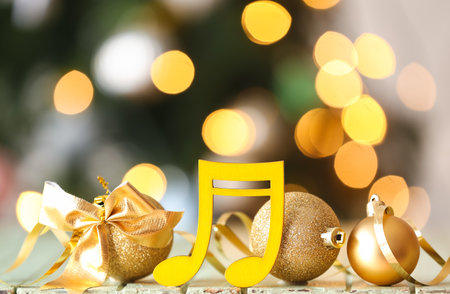 Note sign with balls, bow and serpentine on table against blurred Christmas treeの写真素材