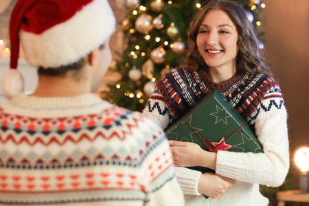Young woman with gift from her beloved husband at home on Christmas eveの写真素材