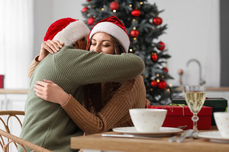 Loving couple hugging at table in kitchen on Christmas eveの写真素材