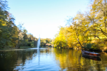 Blurred view of beautiful lake with boat and yellow trees