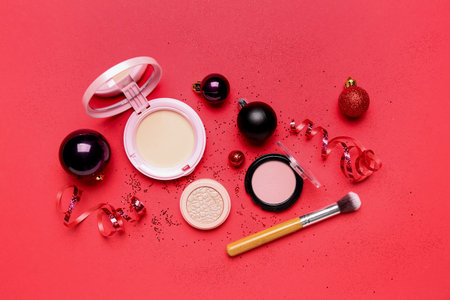 Makeup products with Christmas balls and serpentine on red backgroundの写真素材