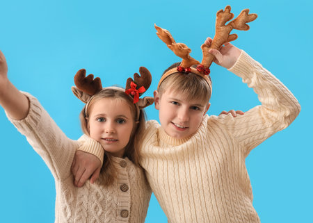 Little children in reindeer horns on blue backgroundの写真素材
