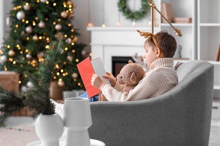 Little boy with toy reading story at home on Christmas eveの写真素材