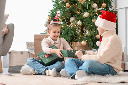 Little children with Christmas presents sitting on the floor at homeの写真素材