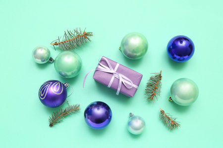 Beautiful composition with Christmas gift, balls and fir branches on color backgroundの写真素材
