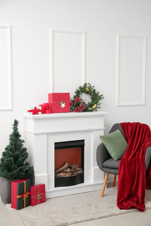 Fireplace with presents, Christmas tree and armchair near light wallの写真素材