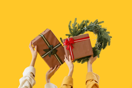 Women with Christmas wreath and gift boxes on yellow backgroundの写真素材