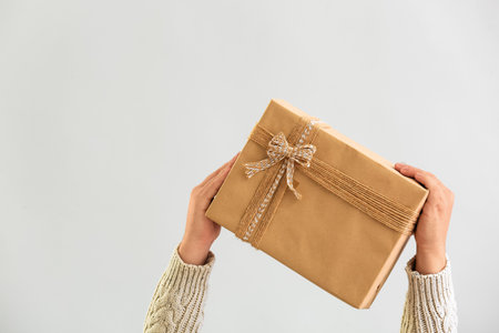 Man with Christmas gift box on gray backgroundの写真素材