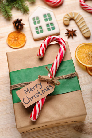 Christmas gift with sweet candy cane on wooden table, closeupの写真素材